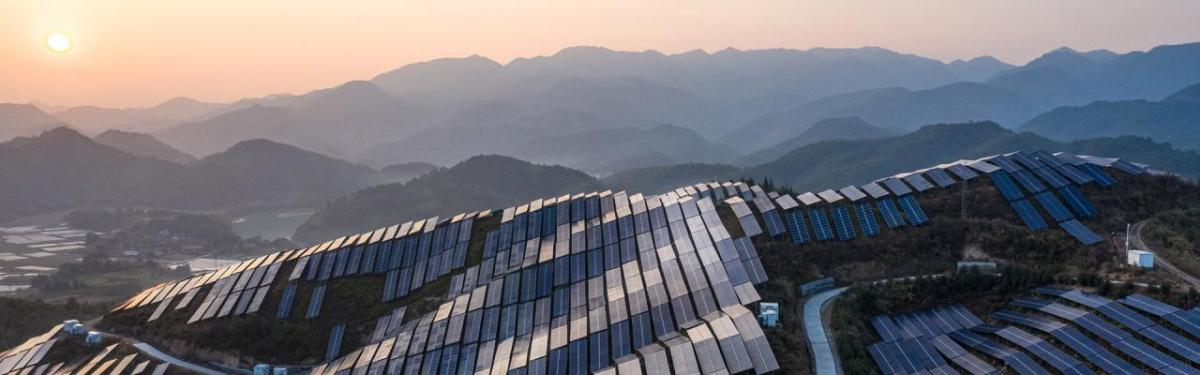 Aerial view of a hilly landscape covered in solar panels.