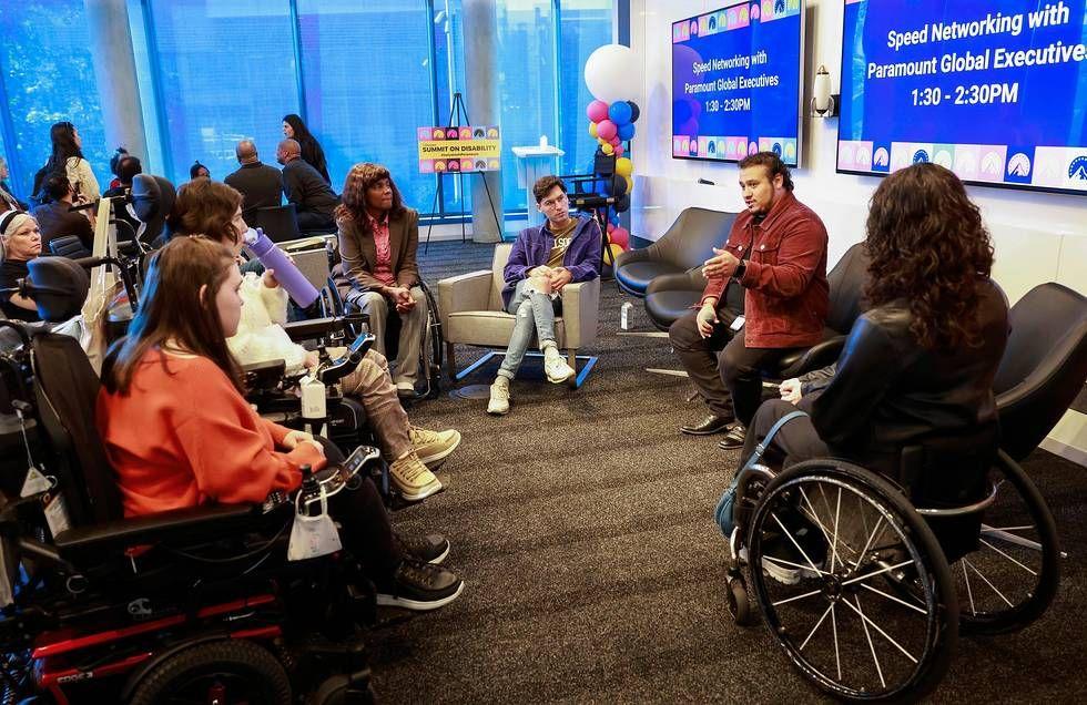 A person speaking with a group of others in a circle around them. "Speed Networking" signs behind them. 