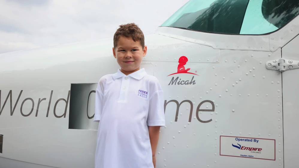 Micah had his plane dedication on Wednesday, August 14, at TPC Southwind ahead of the first day of competition in the FedEx St. Jude Championships. The Purple Eagle program, which began in 2012, names a plane from the FedEx feeder fleet for a St. Jude patient whose parent or grandparent works for FedEx. Photo by Kevin Cody Micah next to an airplane on the ground that shows his name on the side