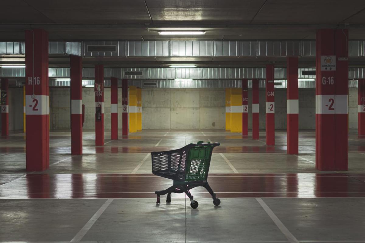 An empty parking garage and a lone grocery cart.