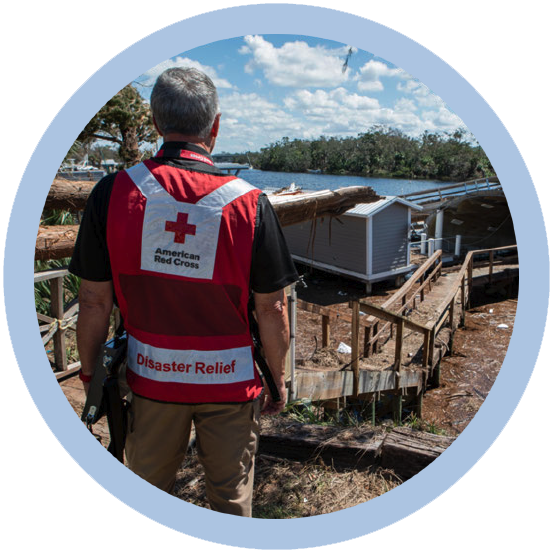 MetLife Foundation’s ongoing support of the American Red Cross helps the organization respond to disasters across the U.S. A person in a Red Cross Disaster Relief vest, looking out at damage