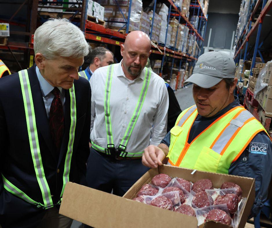 The Senator looks into a box of wrapped meat