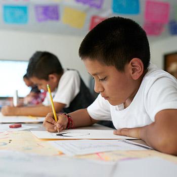 A young school child sat at a table drawing