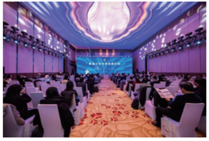People seated in a room with digital display projected on the ceiling and front.