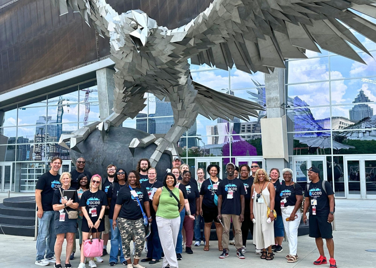 A smiling group posing in front of an eagle sculpture