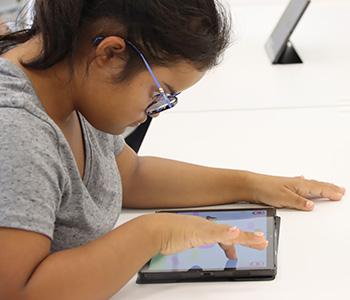 a person sitting at a table using a tablet
