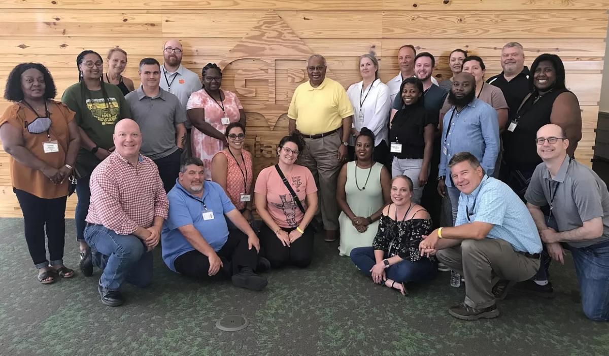 a large group of people in front of a "GP" logo in wood siding