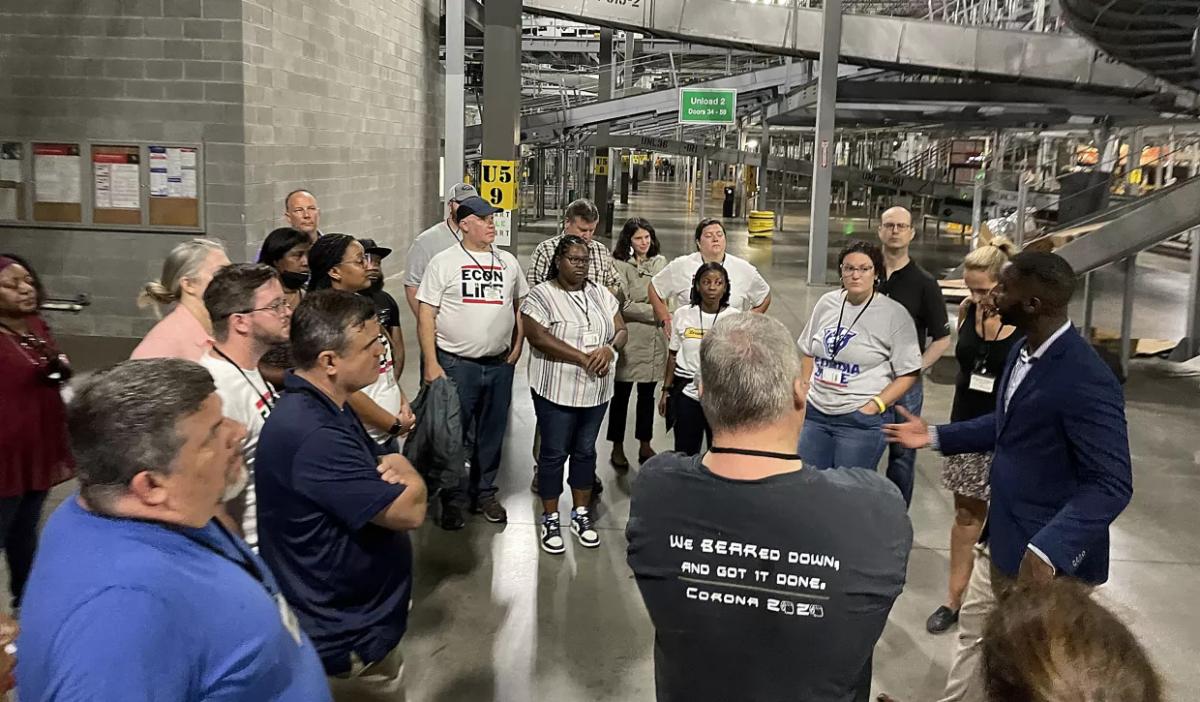 a large group of people on a tour of a UPS facility