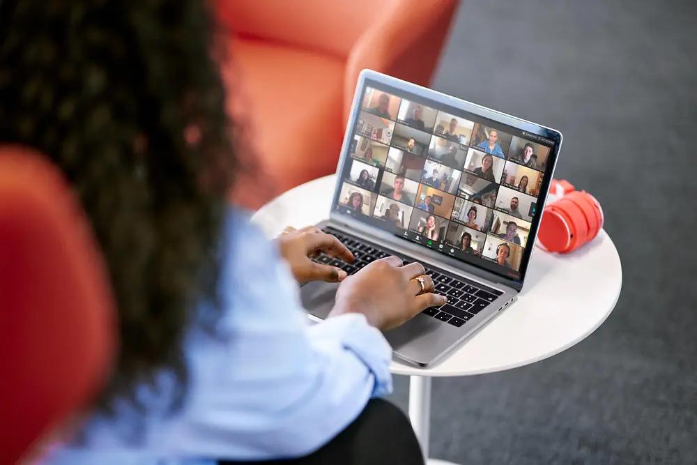 A person attending a virtual gathering with many others on the screen of their laptop.
