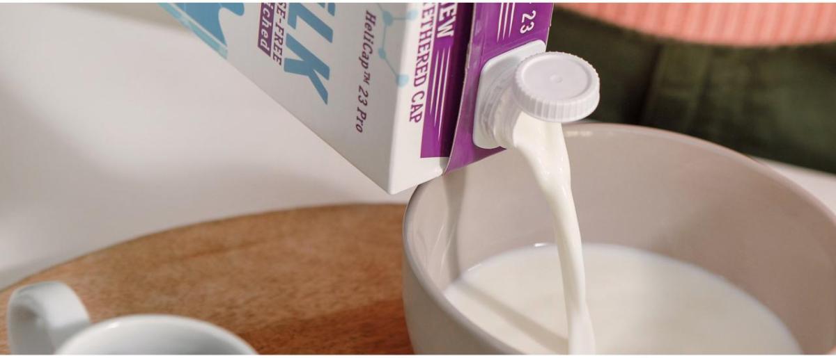 A container of milk being poured into a bowl.