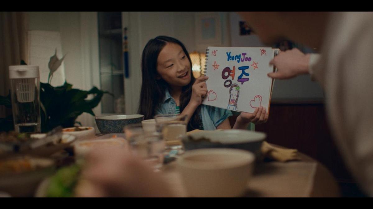 A child holding a hand drawn sign with their name on it.