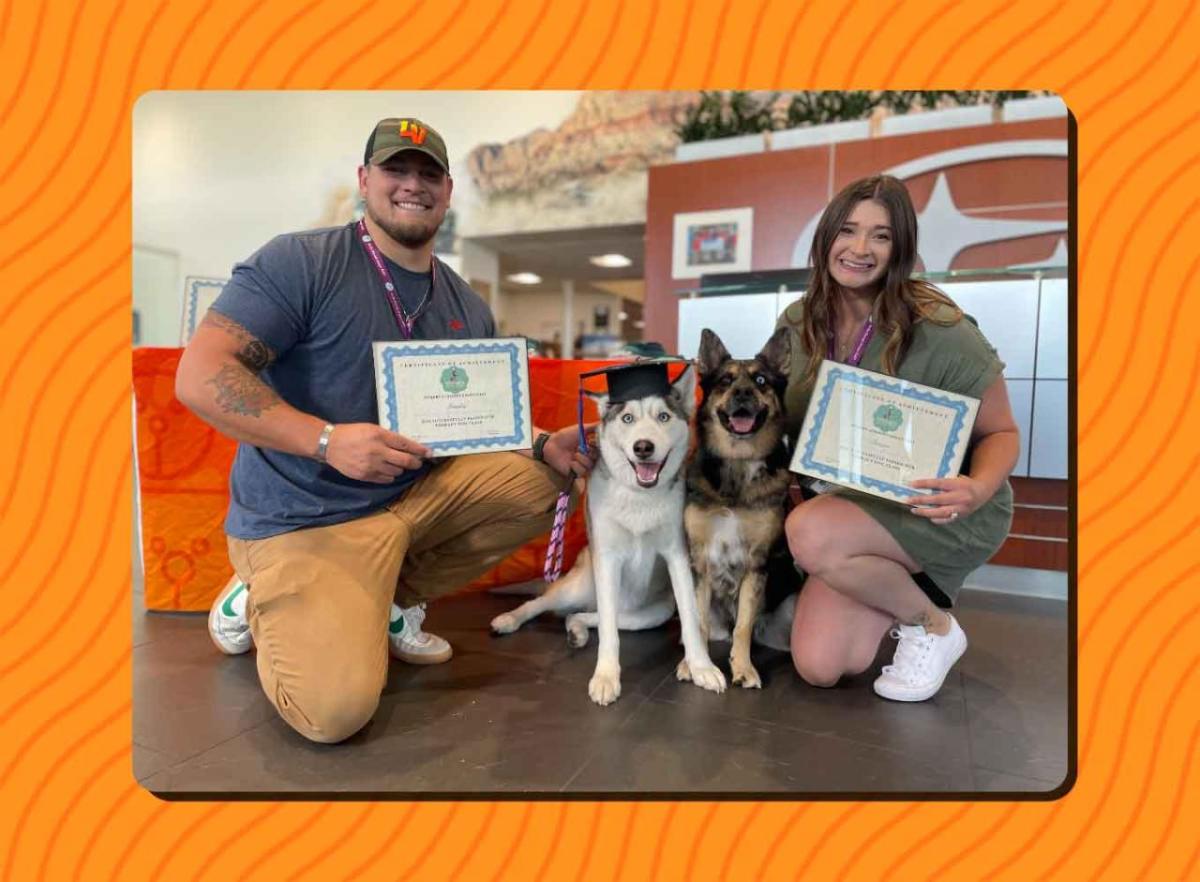 Two people with their dogs and certificates of graduation.
