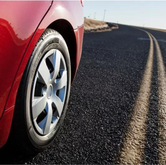 close up of a tire of a red vehicle on black asphalt road