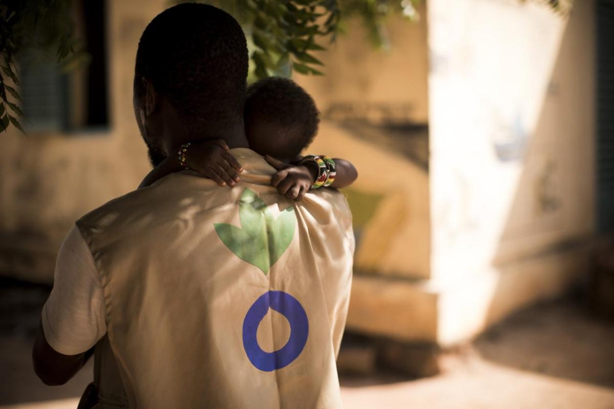 An Action Against Hunger Aid Worker holds a child in his arms in Mali. // Photo by Toby Madden