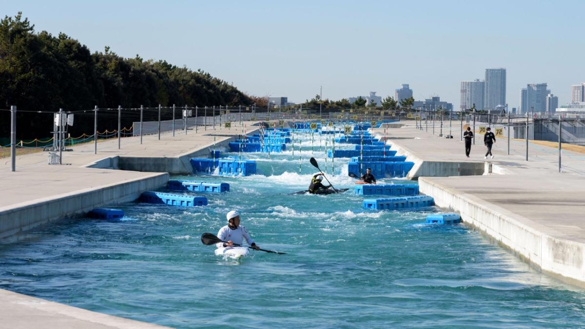 man-made whitewater kayak river, people kayaking don it and some walking along side on the cement walkway