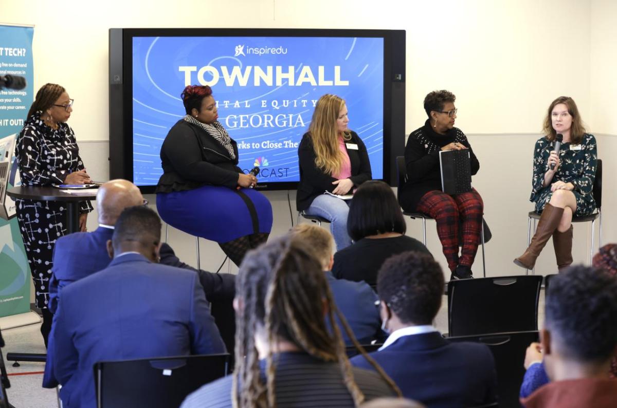 Five people seated on stage with digital display of "Townhwll digital equity Georgia" behind them. A small audience in front.