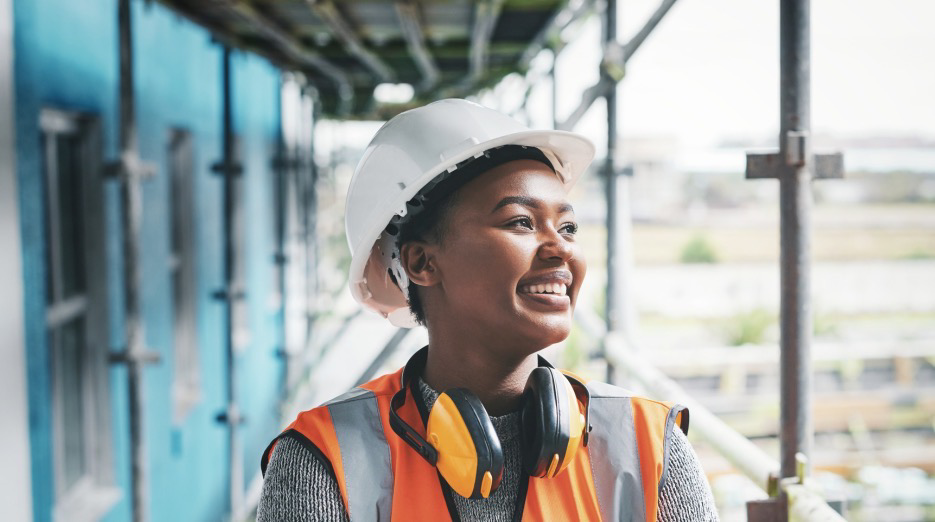 smiling tradeswoman wearing orange vest and hard had