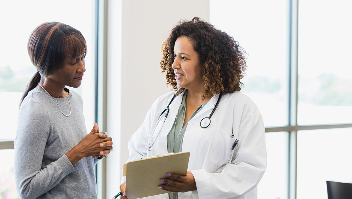 A woman in a lab coat asking questions to a woman