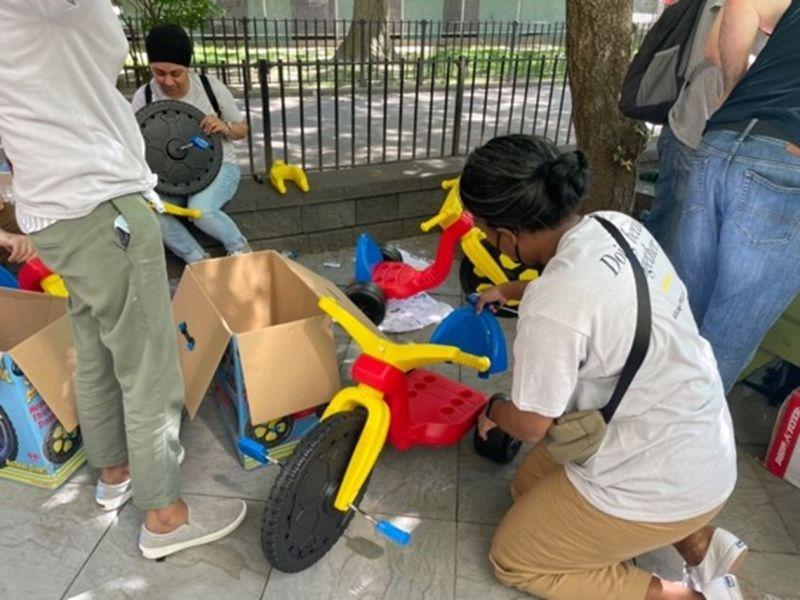 people outside assembling small tricycles