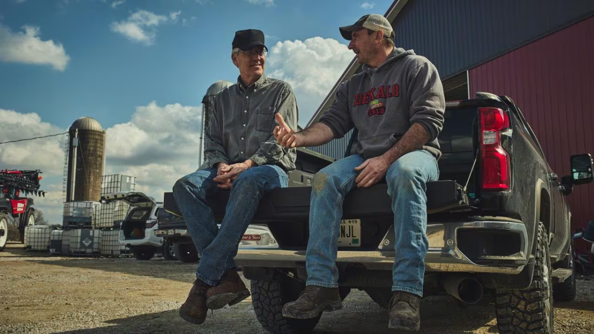 2 farmers talk on a truck bed