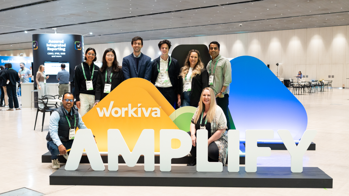People standing around a sign that says, "Workiva AMPLIFY"