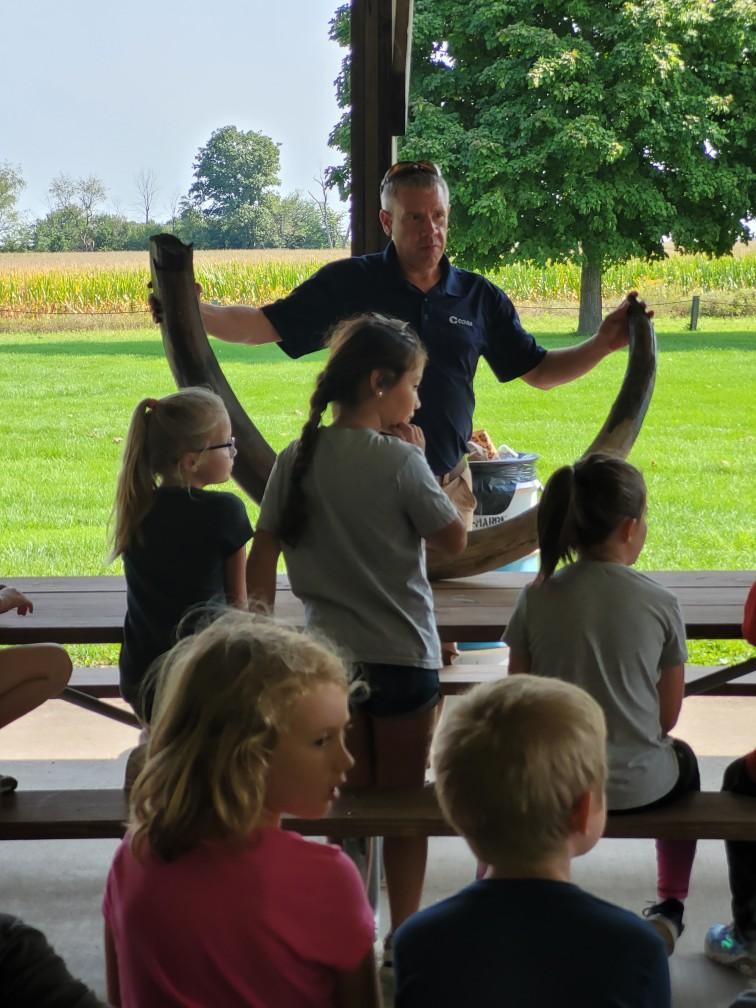 An adult showing a large tusk to a group of children.