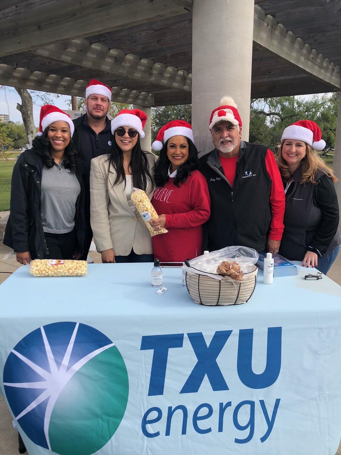 TXU energy table with 6 people with Santa hats