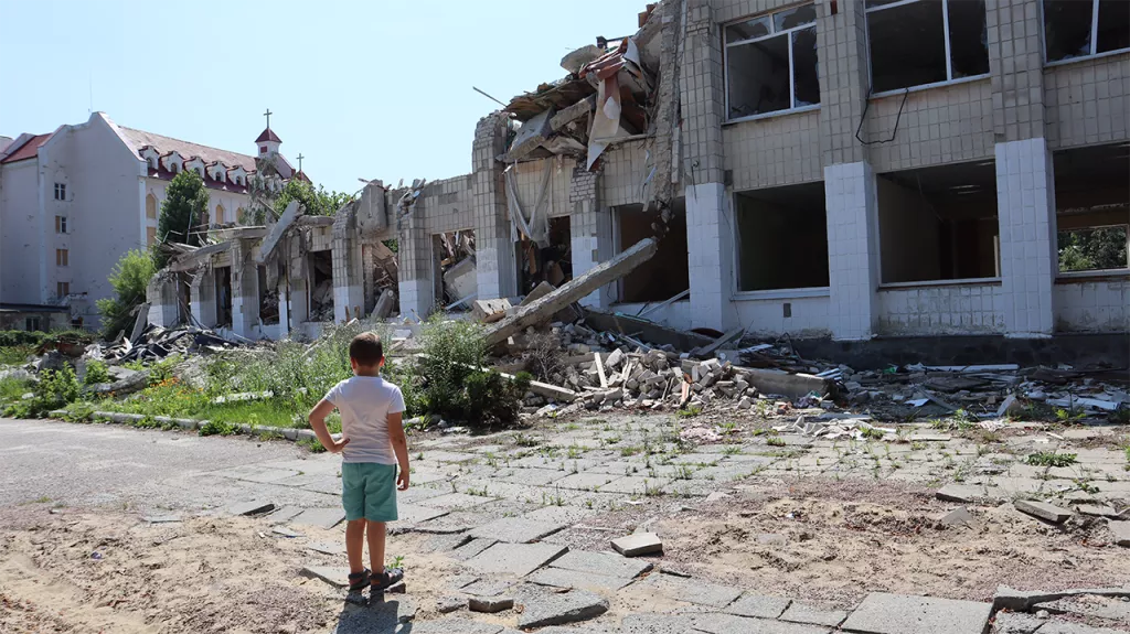 A boy stands in front of a school in the city of Zhytomyr that was destroyed by a Russian missile strike in March 2022. (Nick Allen/Direct Relief)