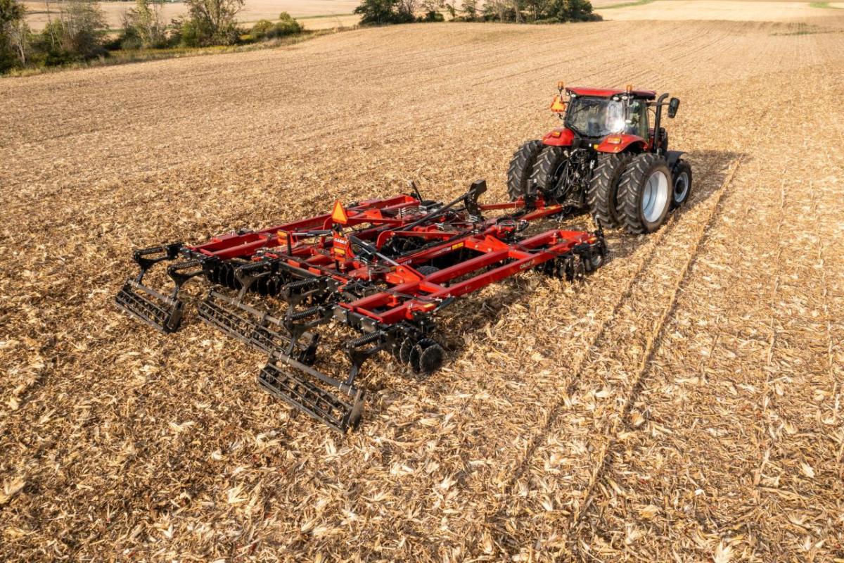 Case IH’s Agronomic Design team works with farmers to ensure the best possible yield from their harvest, with the most efficient use of resources A large red tractor and attached tilling tool on a large harvested crop field.