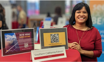 A person leaning on a high stand with displays referring to hiring and applying at SCE.