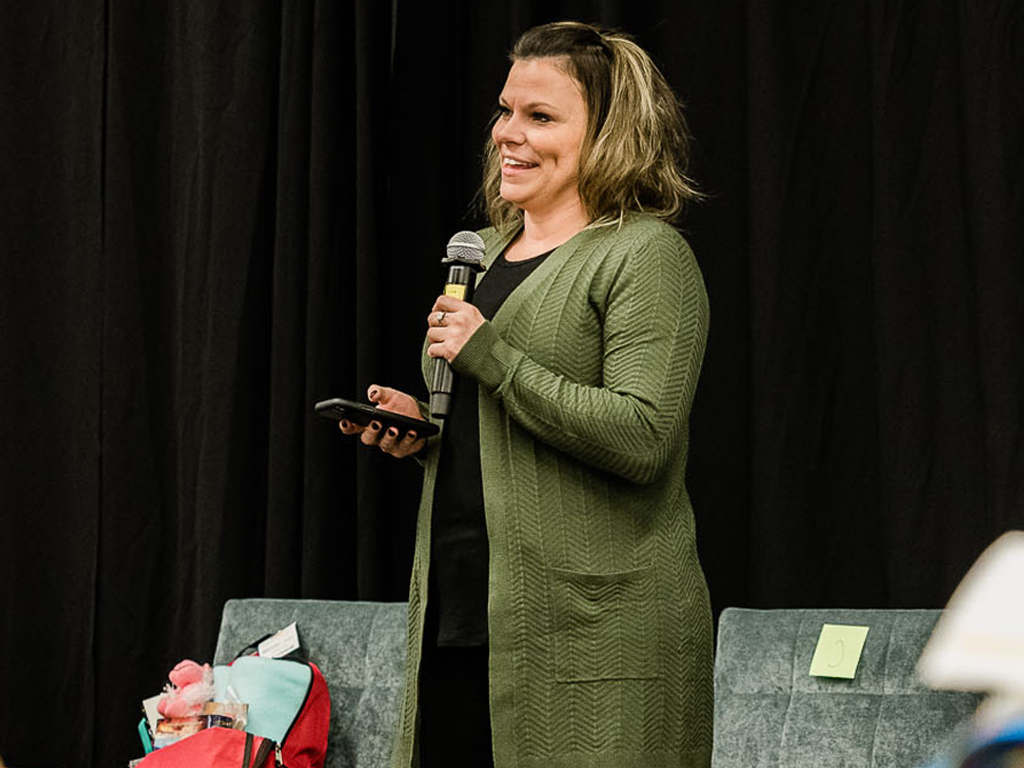 Ashlea Currey in a green cardigan holding a microphone