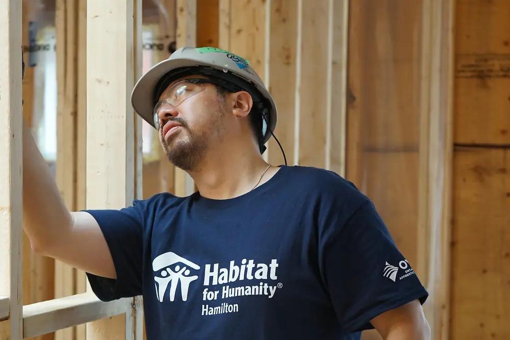 A volunteer inspecting wood framing.