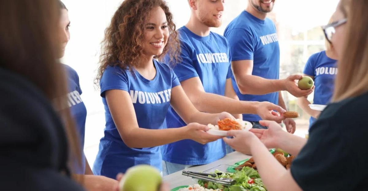 A line of volunteers handing food to others.