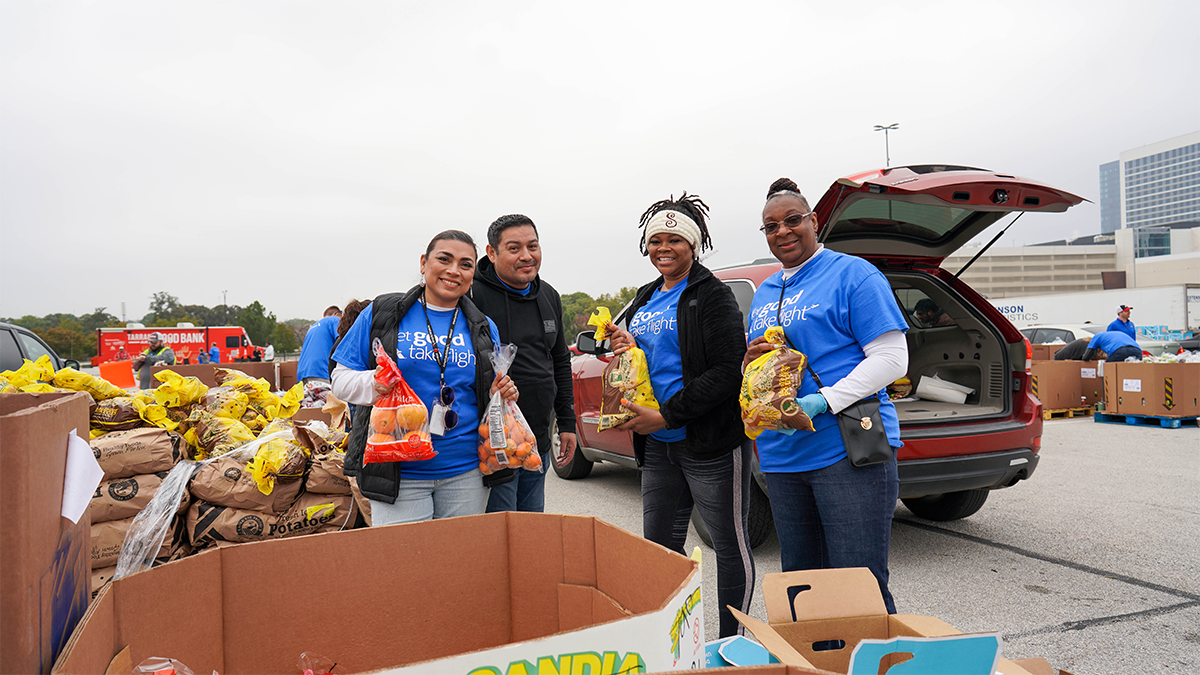 Volunteers packing bags of food into the back of a vehicle.