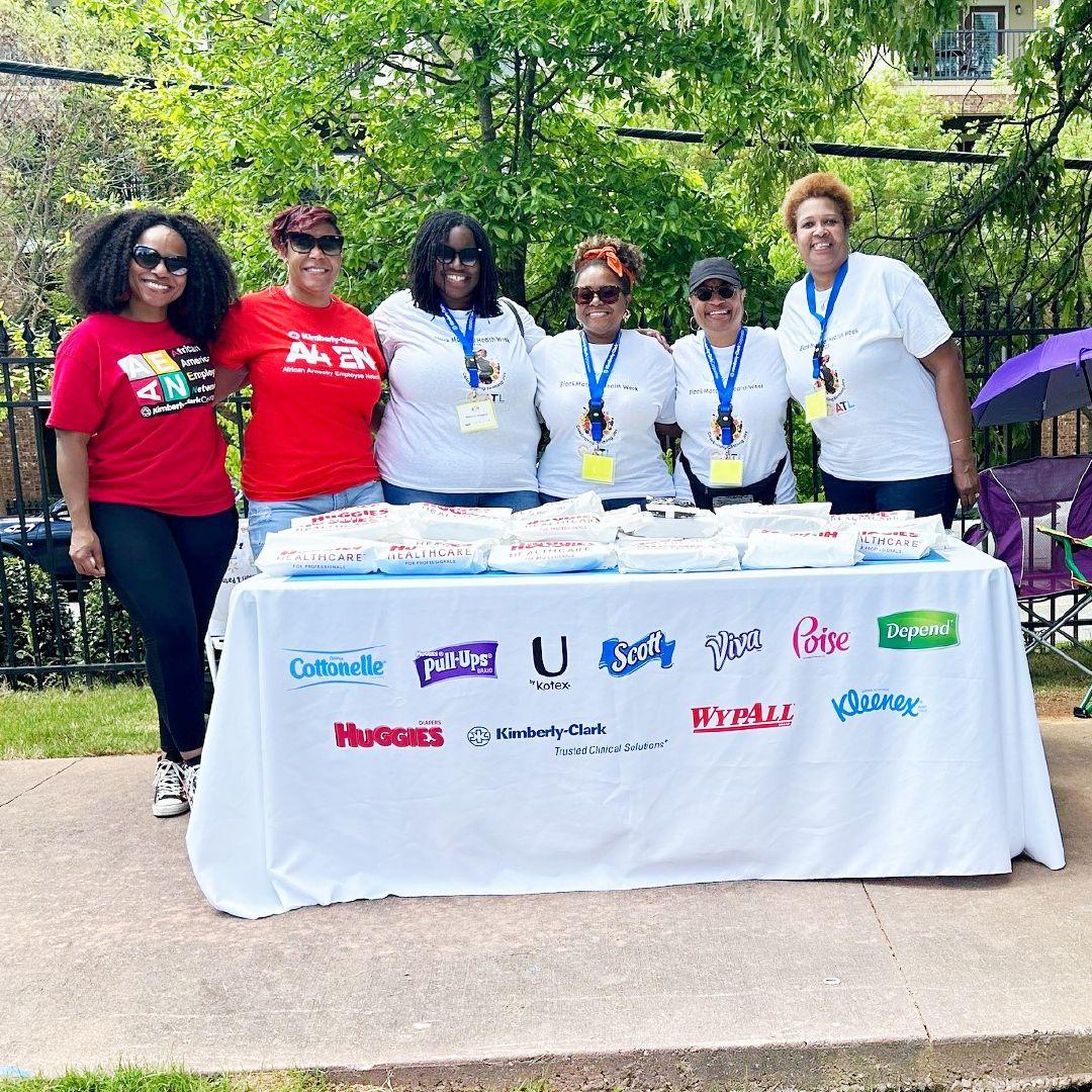 A group of smiling volunteers behind a table outside.