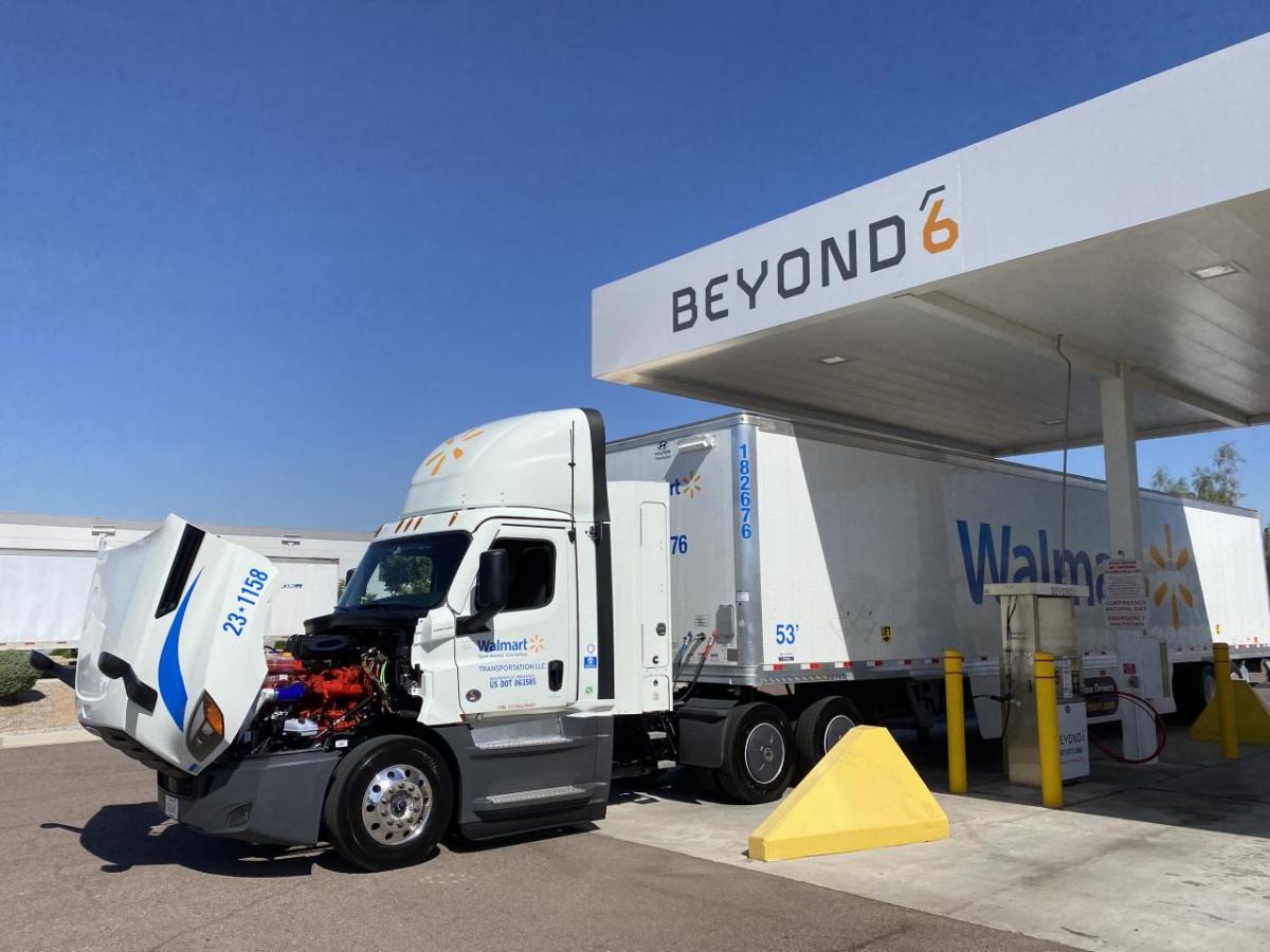A semi truck with the hood open under an overhang with "Beyond" on it.