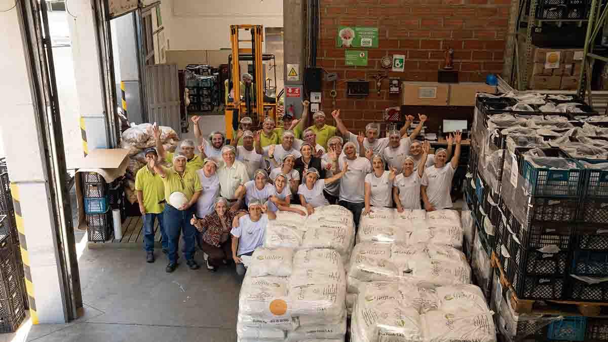 A group of employees posed cheering in a warehouse setting.