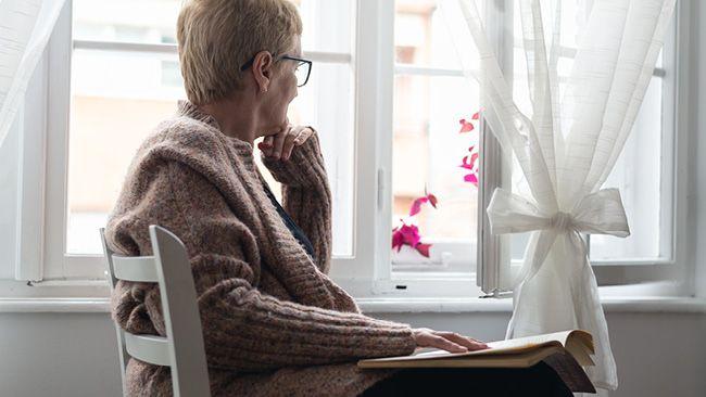 A person seated in a home looking at a book.