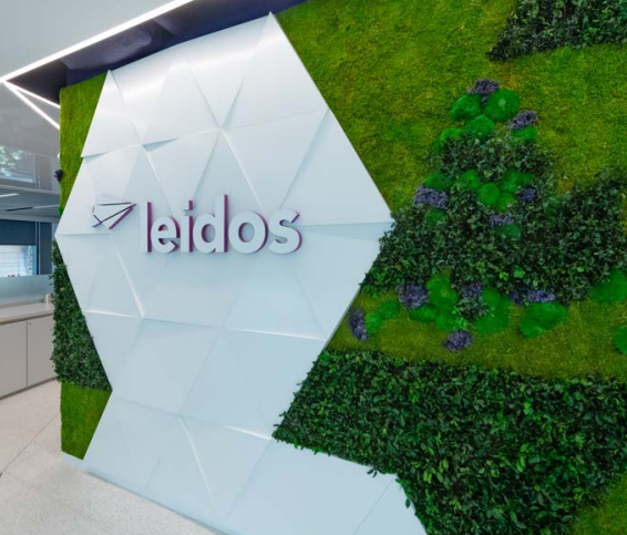 Leidos sign on an interior wall surrounded by greenery.