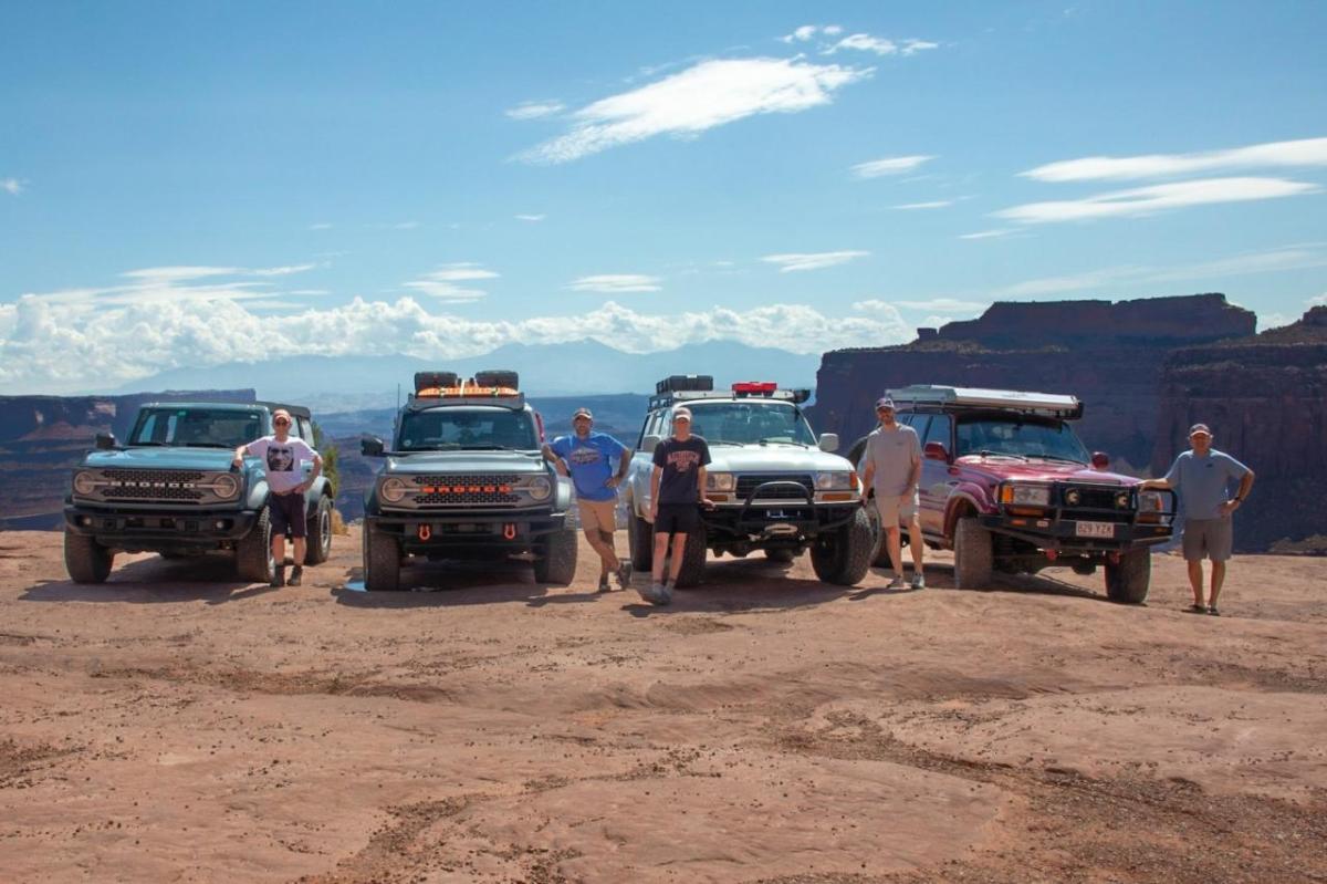 John Mulcahy and family members posed in a scenic natural area each next to an all-terrain vehicle.