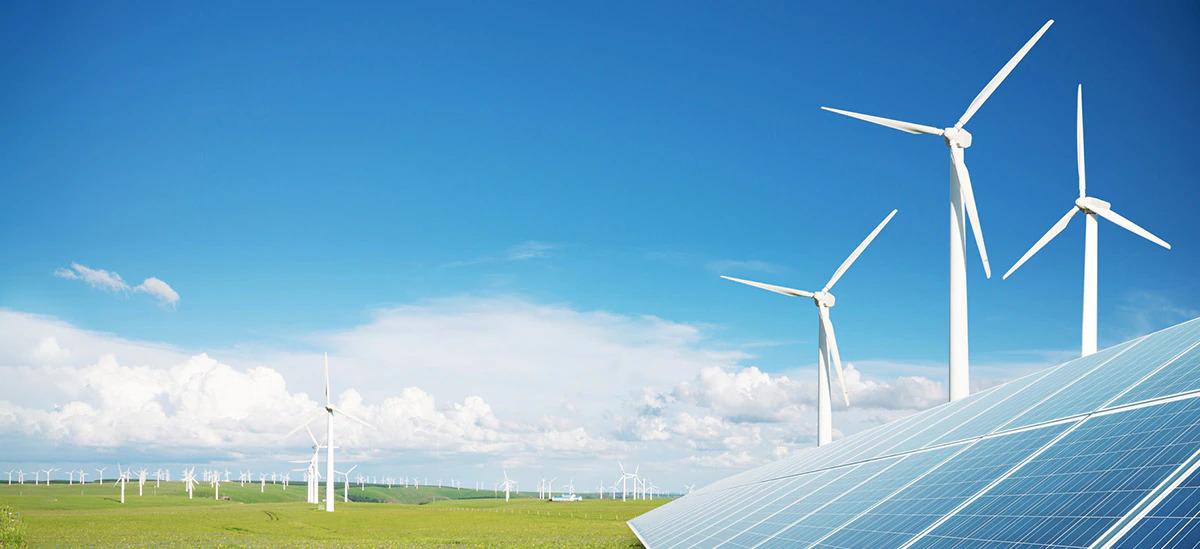 Outside on a bright day, windmills scattered on a large flat plain of grass, a solar panel in the right corner