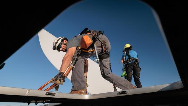 Two people working at the top of a wind turbine
