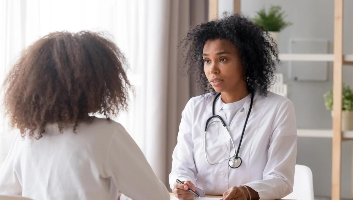 two people talking across from each other, wearing white lab coats, one has a stethoscope around their neck