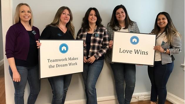 From left, Women Aware’s Catherine Cintron, Melinda Clugsten, Josephine Mingione, Maria Betanzos and Maliha Janjua sport jeans at Denim Day, an international movement to “wear jeans with a purpose,” stand in solidarity with survivors of sexual assault, and promote awareness and education. 5 women holding signs that read: "Teamwork Makes the Dream Work" and "Love Wins"