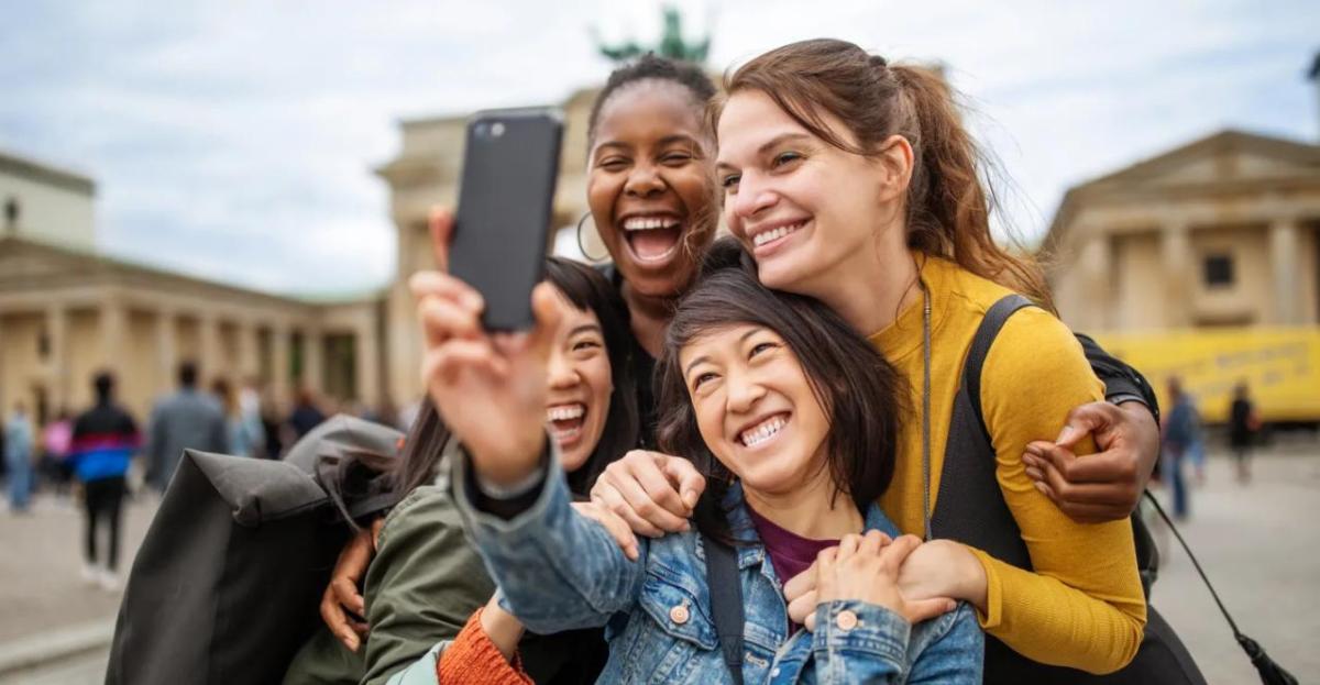 Four smiling people taking a selfie together outside