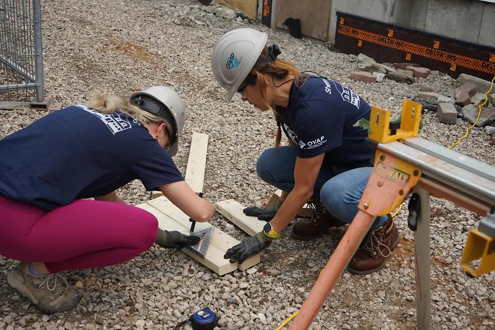 Two volunteers measuring a piece of wood.