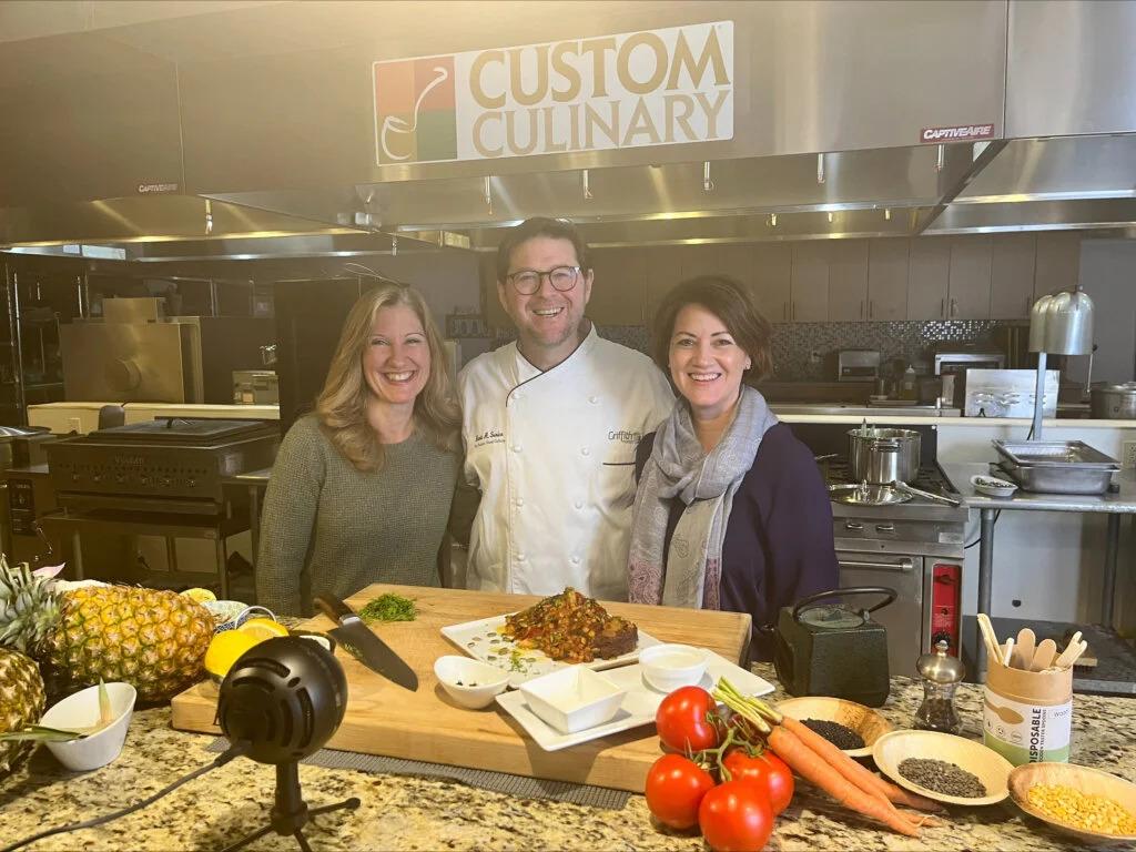 Three people posed in a kitchen.