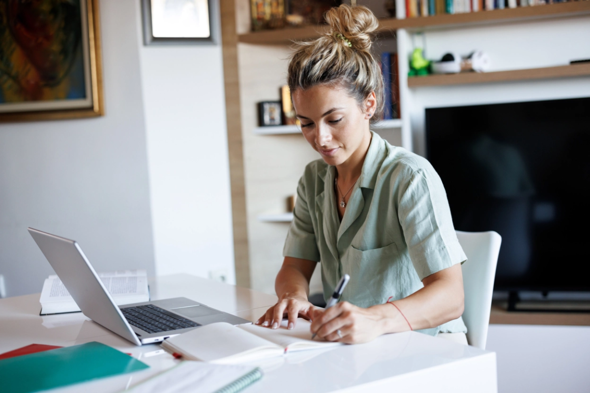 Young woman taking notes while learning from home " "