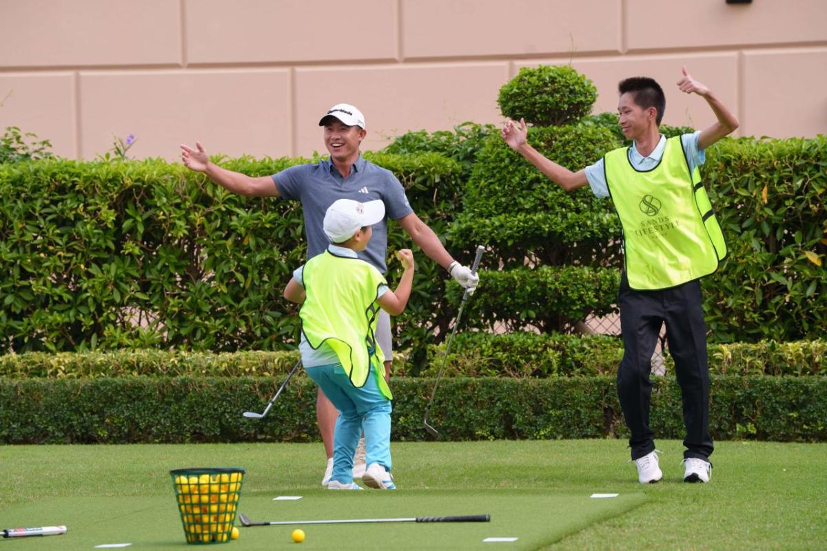 Adults and a child jumping in excitement, holding golf clubs on a green.