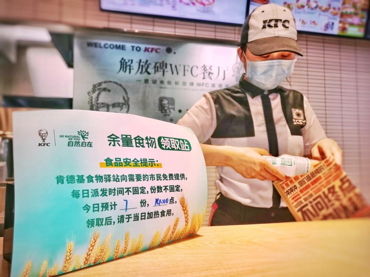 KFC China worker bags food next to a sign for the food bank